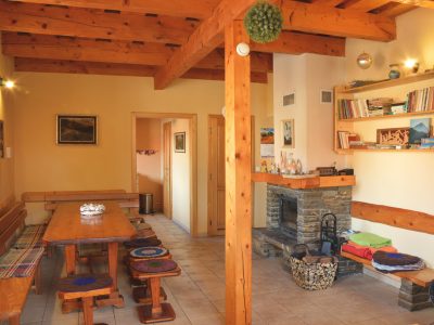 Spoločenská miestnosť s murovaným krbom a drevené trámy.
